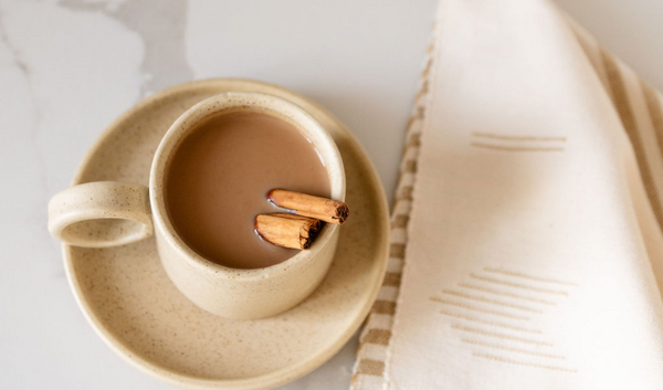 Handcrafted ceramic cup with cafe de olla, cinnamon stick and tea towel on a kitchen counter