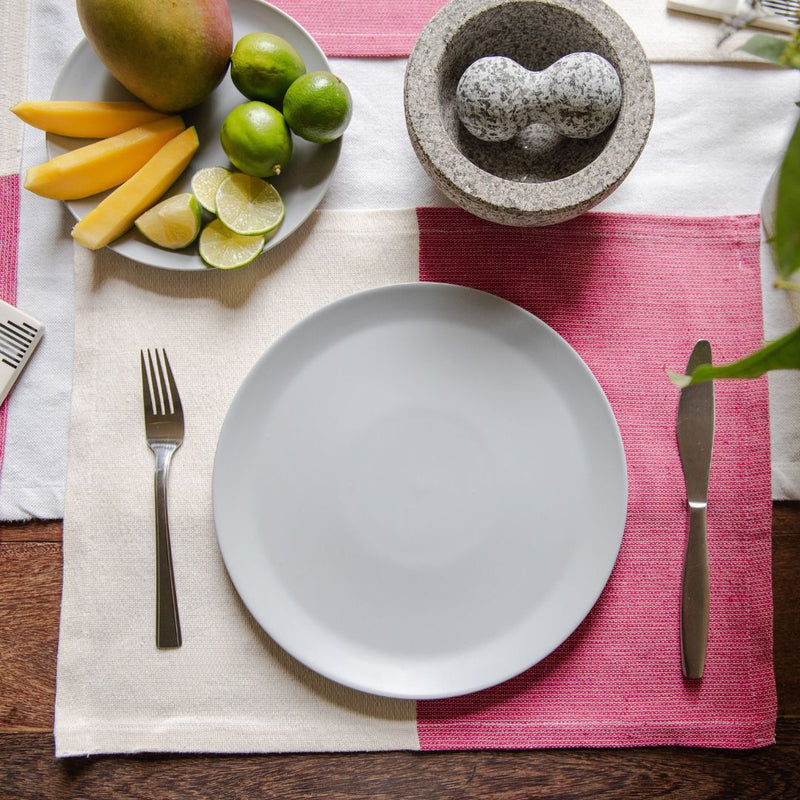 Rosa Mexicano (magenta) placemat with neutral color block placemat with a plate of mango and limon and a molcajete