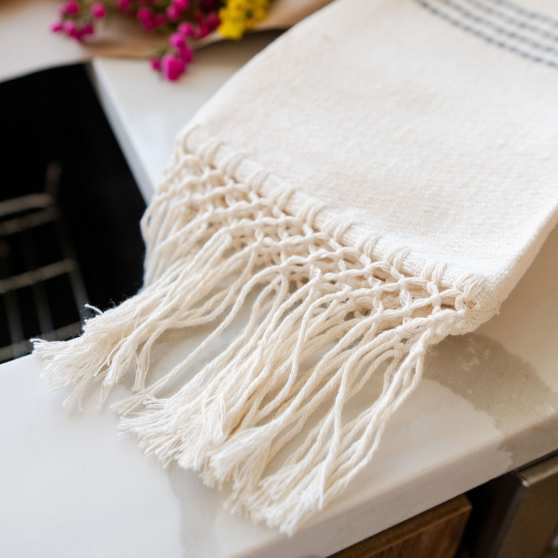Closeup of 100% cotton fringe on woven kitchen towel laying flat by the sink
