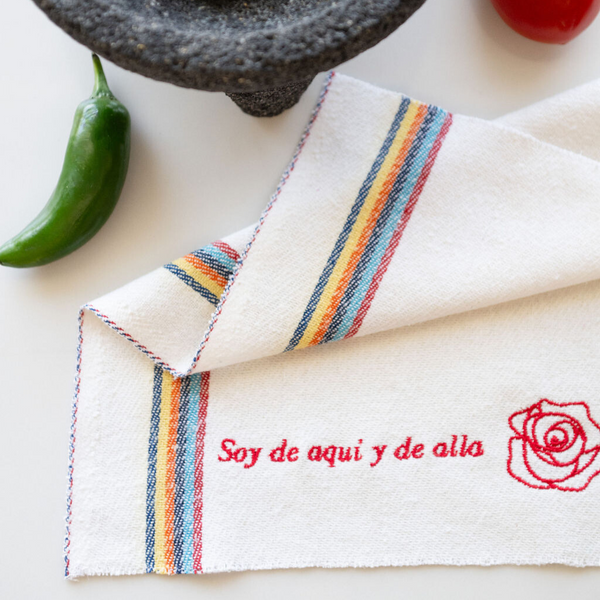 white recycled cotton cleaning cloth known as Jerga in Mexico with red embroidery and red rose on a counter with a molcajete 