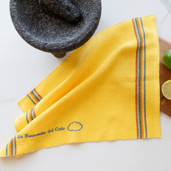 yellow recycled cotton cleaning cloth known as Jerga in Mexico with blue embroidery. A blue cloud embroidered on the cloth and a phrase reading "Un rinconcito del cielo"