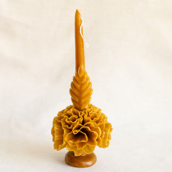 Artisanal Oaxacan floral taper beeswax candle in amber gold standing on a base.