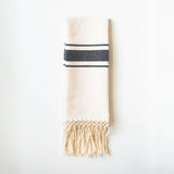 Beige towel with black stripes and fringes on a white background