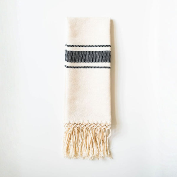 Beige towel with black stripes and fringes on a white background