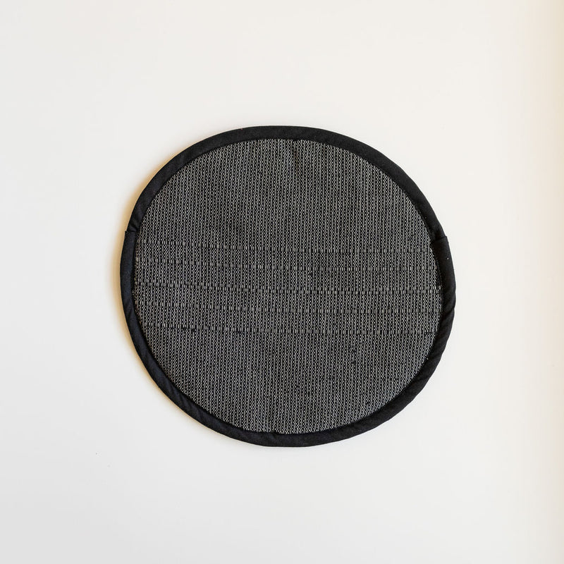 A Black Handwoven Cotton Tortilla Warmer sits elegantly on a table, showcasing its natural, dark tones and intricate handwoven texture. Made from 100% cotton, this eco-friendly warmer adds a rustic, artisan touch to any meal while keeping tortillas warm and fresh.