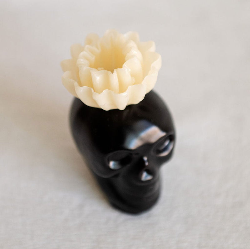 Black Obsidian Skull Candle with a white flower top, made from 100% beeswax, perfect for home decor or altars, offering a unique blend of bold design and natural elements.