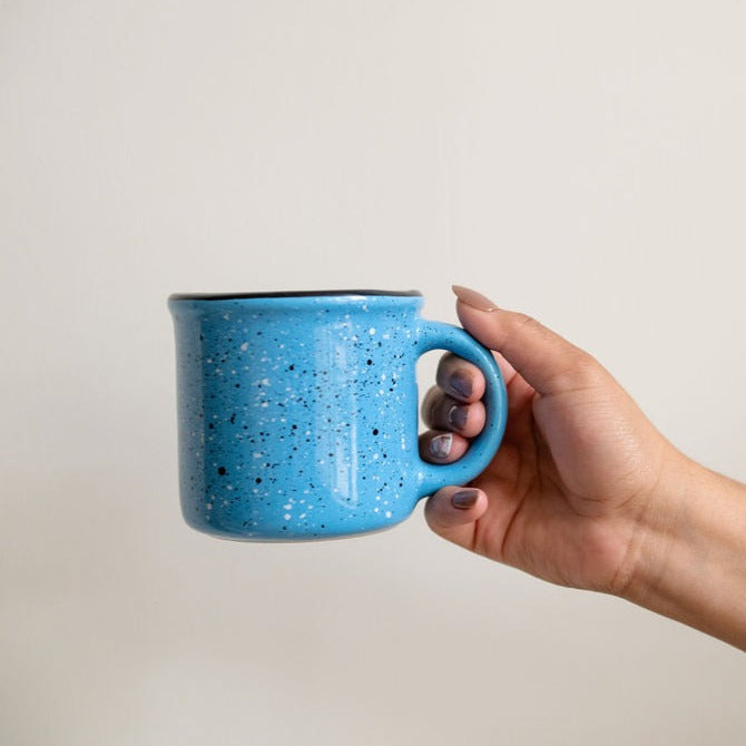 Blue Speckled Ceramic Coffee Mug (Mexican peltre style) with Black Rim held by a hand