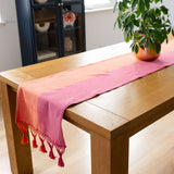 Color Block Pink and Orange Cotton Table Runner with tassels on a wood table with a planter on top