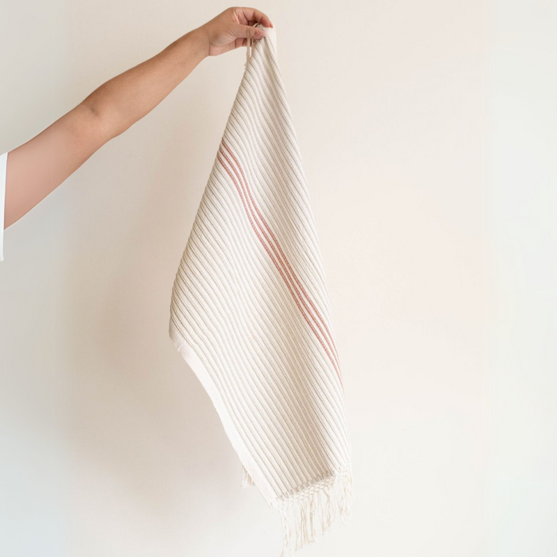 A Corded Handwoven Cotton Hand & Tea Towel with three cinnamon stripes hanging from a hand.