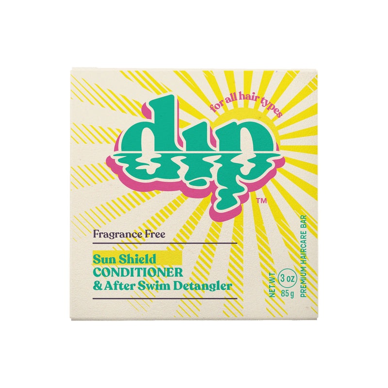 A fragrance-free Sun Shield Dip Conditioner Bar, presented in a simple, eco-friendly box. The packaging highlights the product's key features, with "Fragrance Free Sun Shield Dip Conditioner Bar" clearly labeled. The conditioner bar has a smooth, solid texture, promising protection and nourishment for sun-exposed hair.