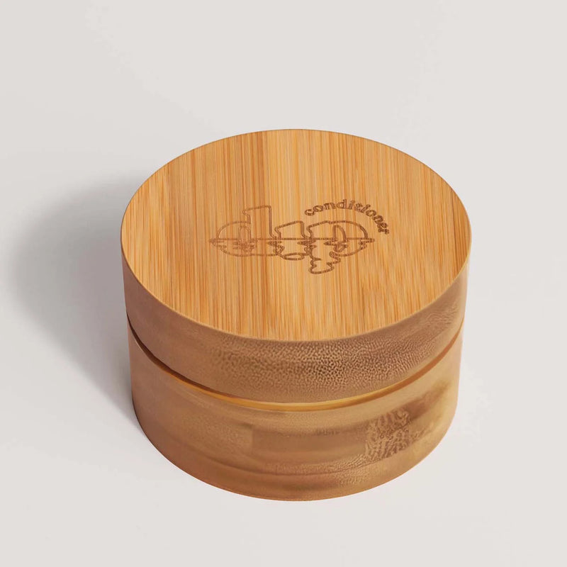 Eco-friendly bamboo travel case with a lined lid and inner coaster, designed to protect and dry a full-sized conditioner bar during travel.