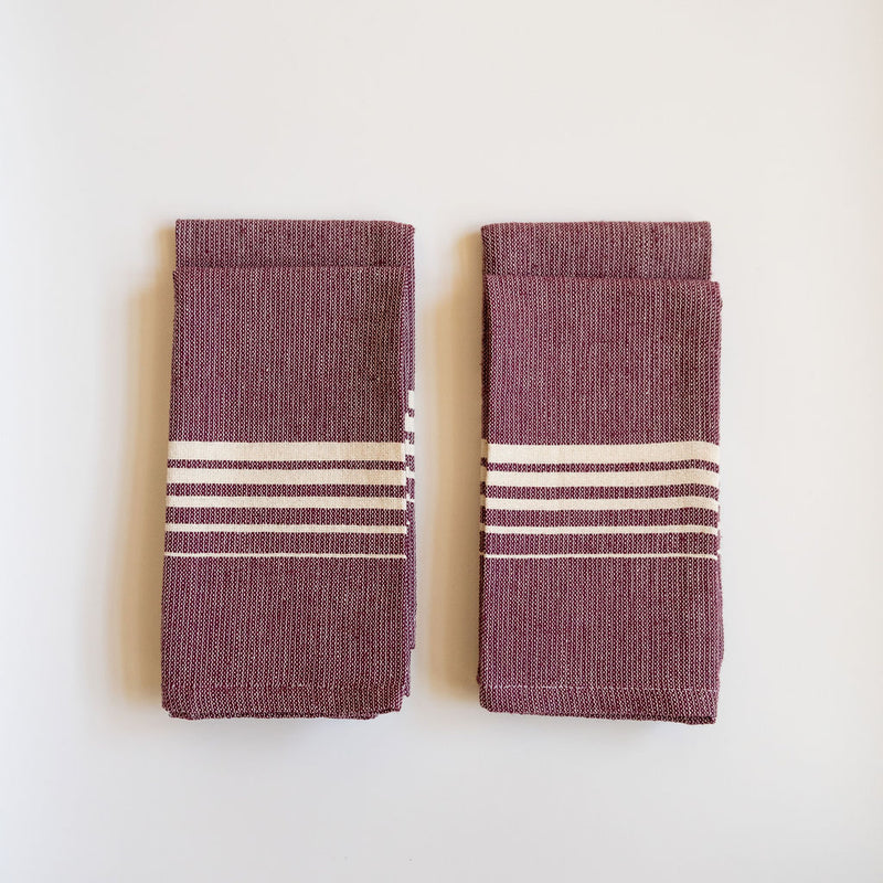 Set of four Purple Jacaranda Casa Oaxaca Cotton Napkins feature a rich, purple hue adorned with five evenly spaced white lines, creating a striking contrast. Handwoven from 100% Mexican cotton, this eco-friendly napkin adds a vibrant, artisanal touch to any sustainable table setting, perfect for eco-conscious dining.