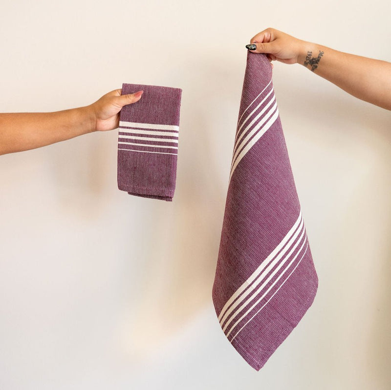 Set of two Purple Jacaranda Casa Oaxaca Cotton Napkins feature a rich, purple hue adorned with five evenly spaced white lines, creating a striking contrast. Handwoven from 100% Mexican cotton, this eco-friendly napkin adds a vibrant, artisanal touch to any sustainable table setting, perfect for eco-conscious dining.