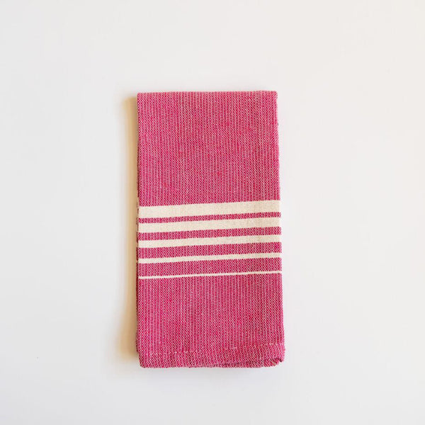 A vibrant Rosa Mexicano (Pink) Casa Oaxaca Woven Cotton Napkin, showcasing artisanal craftsmanship from Oaxaca, Mexico, with a soft, durable texture perfect for adding a pop of color to any table setting. This eco-friendly, 100% cotton napkin is handwoven, blending sustainable design with traditional Mexican culture.