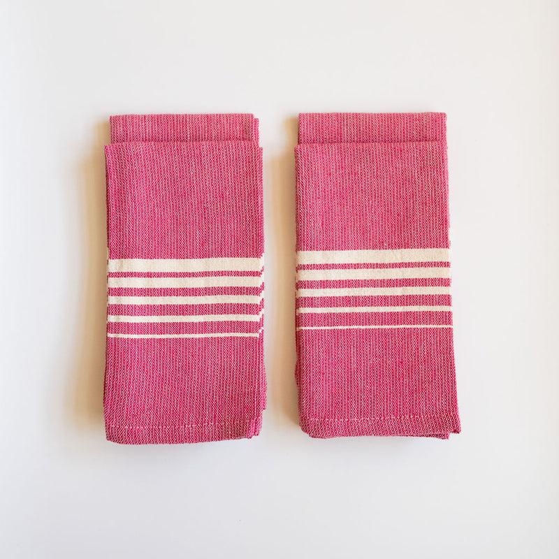 A vibrant Set of Four Rosa Mexicano (Pink) Casa Oaxaca Woven Cotton Napkins, showcasing artisanal craftsmanship from Oaxaca, Mexico, with a soft, durable texture perfect for adding a pop of color to any table setting. This eco-friendly, 100% cotton napkin is handwoven, blending sustainable design with traditional Mexican culture.