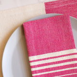 Closeup of rosa mexicano pink cotton woven napkins with white stripes