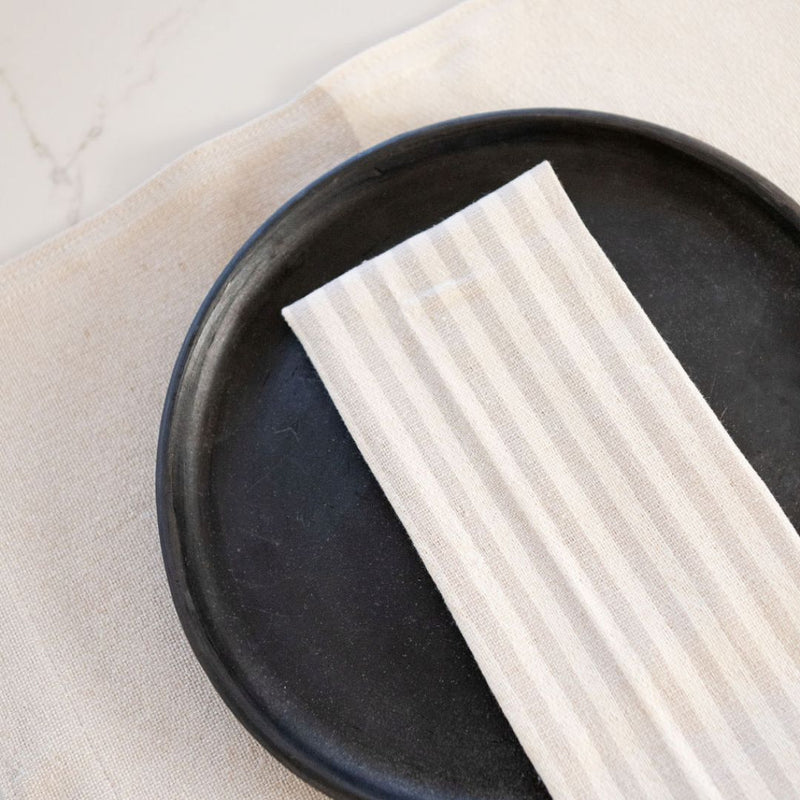 Stripped White/Beige Cotton Napkin on black plate placed on top of Color Block White/Beige Cotton Placemat