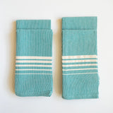 A vibrant Set of Four Teal Casa Oaxaca Woven Cotton Napkin, crafted from 100% Mexican cotton, adds a pop of color to any table setting with its artisanal design and sustainable, eco-friendly material. Perfect for elevating your dining experience, this napkin is handwoven in Oaxaca and designed to complement a modern, conscious lifestyle.