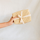 A handcrafted palm gift box being handed from one had to another