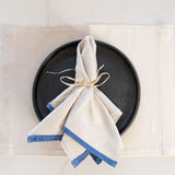 Grey and Beige placemat with a black plate and oversized dinner napkin with blue border