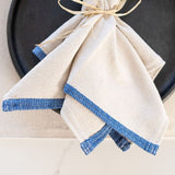 Closeup of a black plate and oversized beige dinner napkin with blue border