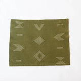 Olive green cotton table cloth and cloth napkin with geometric patterns on a white background