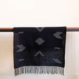 Sacred Lines Handwoven Cotton Table Runner in Black with white geometric patterns draped over a wooden table against a white background