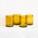 Four amber gold glass tumblers on a white background