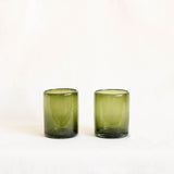 Two olive green glass tumblers on a white background