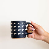 Hand holding Tzintzuntzan handmade ceramic mug with clouds pattern, burnished clay pottery from Michoacán Mexico, natural matte finish coffee cup