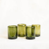 Four olive green glass tumblers on a white background