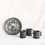 Ceramic plate with a mermaid design and three matching mugs on a white background