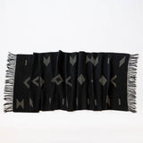 Sacred Lines Handwoven Cotton Table Runner in Black with white geometric patterns and fringe on a white background