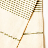 A close-up of a cream-colored woven hand towel featuring thin horizontal olive green dotted stripes.