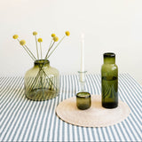Handblown Recycled Glass Candle Holder, flower vase, cup, and carafe paired with cotton strip tablecloth and palm placemat all made in Mexcio.