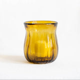 An amber yellow translucent handblown glass candle holder with a fluted, ribbed texture, shown on a plain white background.