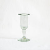 A small clear glass candle holder with a flared rim and a short stem, photographed against a plain white background.