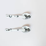 set of two stylized dog or wolf-like creatures (nahual) with sharp teeth and distinctive features on the enamelware peltre metal spoon