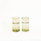 Two olive green handblown glass tumblers on a white background