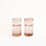 Set of two handblown amethyst plum highball glass tumblers with water inside against white background
