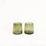 Two handblown olive green glass optic tumblers on a white background