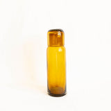 Amber glass bedside carafe bottle with lid on a white background