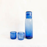 Set of Mexican blue glassware including a bottle carafe and two tumblers on a white background