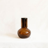 Chocolate brown glass carafe with a dark brown glass lid on a white background