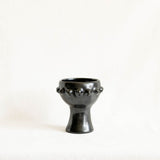 A black ceramic incense or candle holder with a flared rim and a short pedestal base, photographed against a plain off-white background.