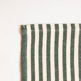 Closeup of a cotton napkin with olive green and beige vertical stripes on a white background
