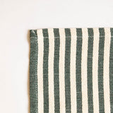 Close up of a hemmed corner of the green striped cotton tablecloth