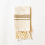 Beige cotton hand towel with striped pattern and fringes on a white background