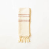 A handwoven cream-colored woven hand towel with cinnamon brown horizontal woven stripes and fringe at the bottom, photographed against a plain white background.