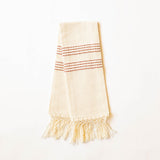 A handwoven cream woven hand towel with cinnamon brown horizontal woven stripes and fringe at the bottom, photographed against a plain white background.